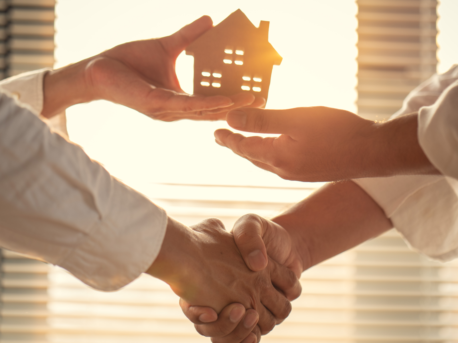 Deux personnes se serrant la main avec une maison miniature pour illustrer le financement d’un achat immobilier.
