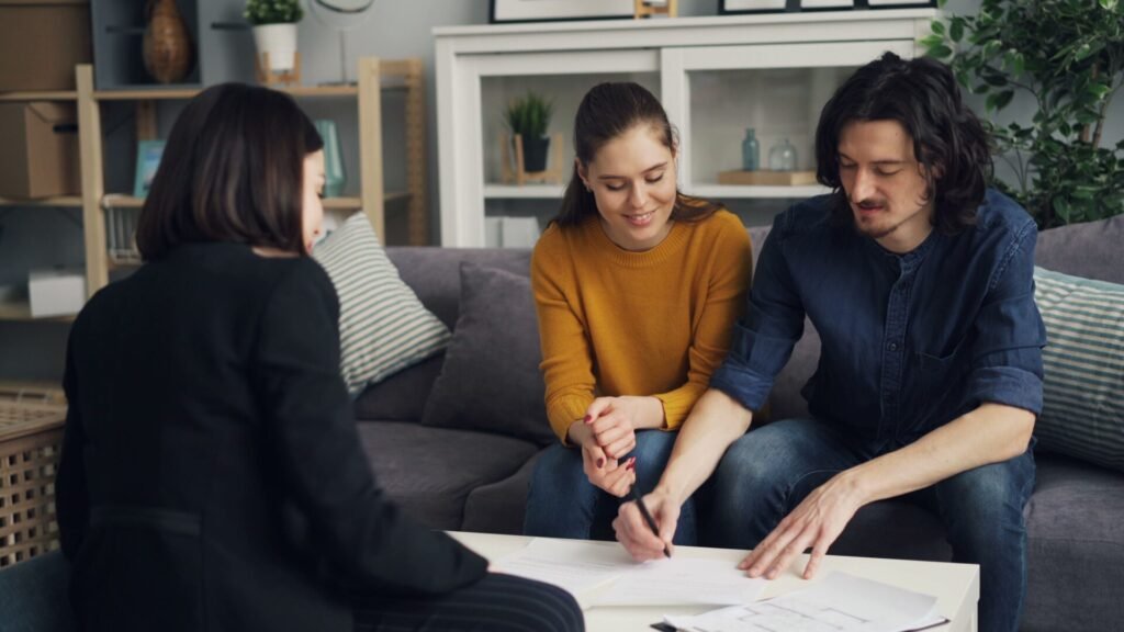 Couple en rendez-vous avec un conseiller pour préparer un dossier de prêt immobilier avant un achat immobilier.
