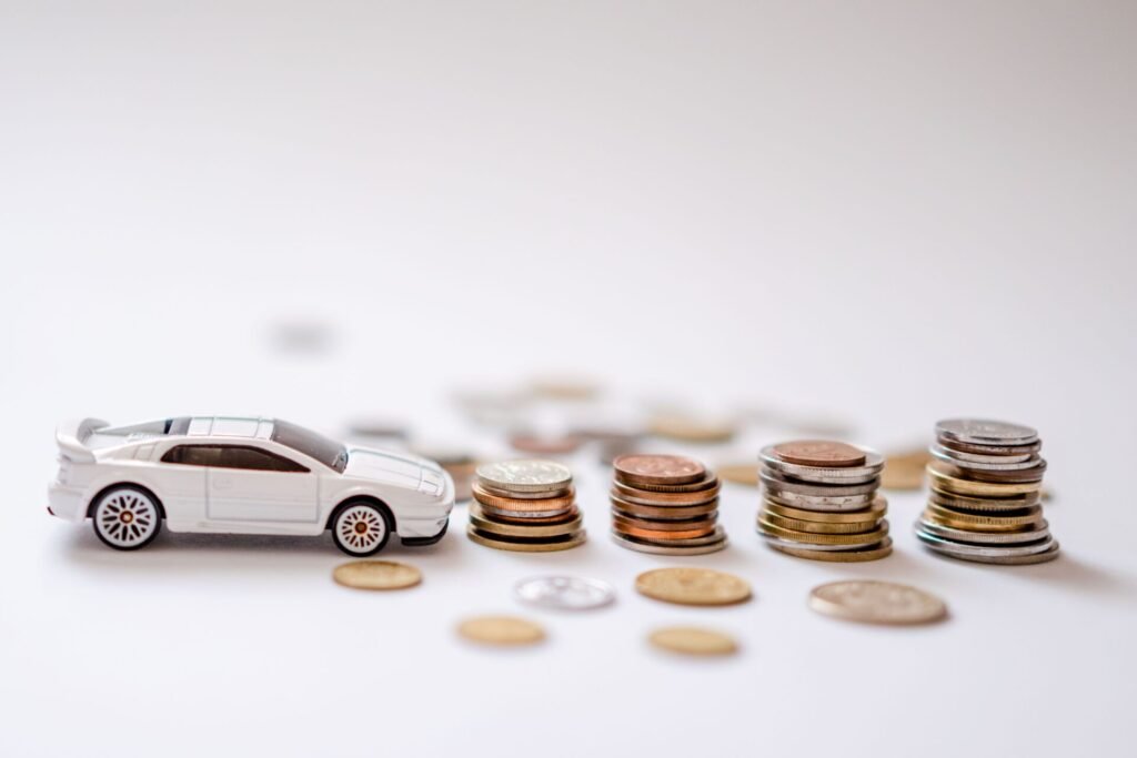 Voiture miniature à côté de piles de pièces illustrant l’impact d’un crédit auto sur un prêt immobilier.