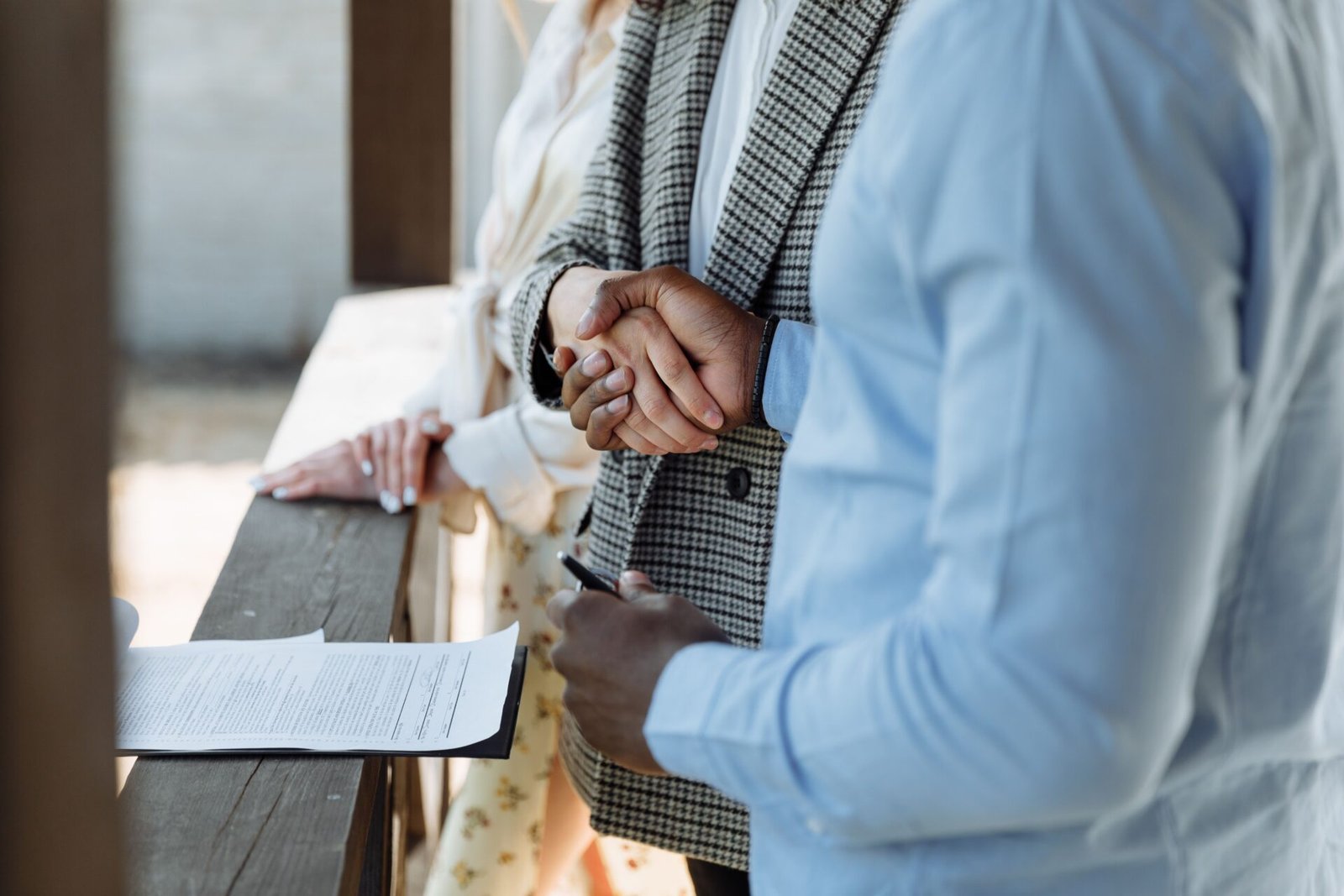 Poignée de main entre deux personnes au-dessus d'un contrat, illustrant un compromis de vente immobilier.