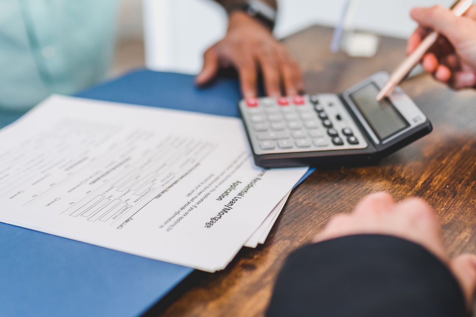 Deux personnes examinent une demande de prêt immobilier avec une calculatrice et des documents bancaires.